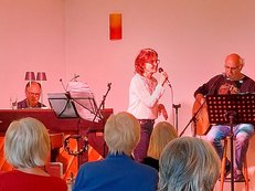 Sängerin mit zwei Musikern vor Café-Publikum